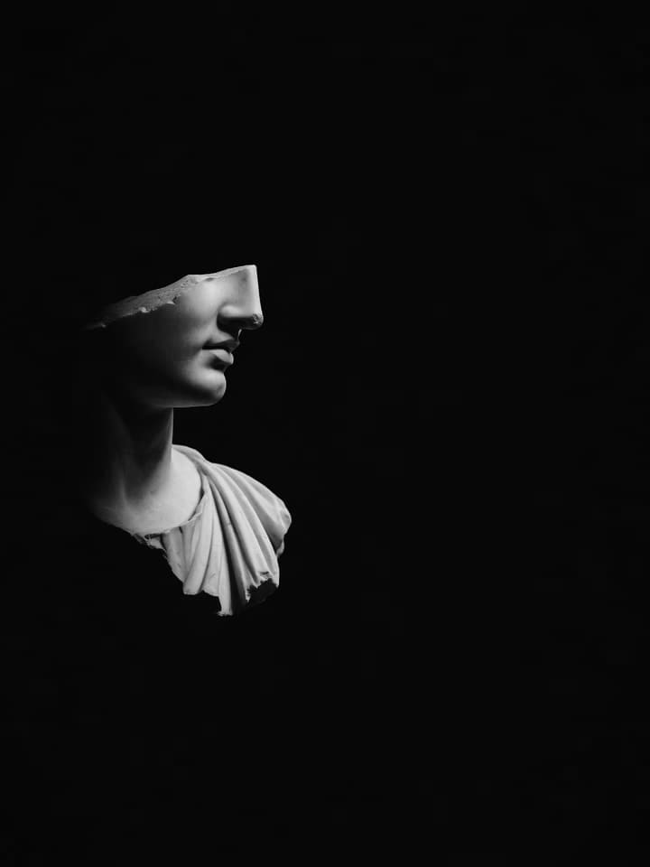 Classical marble bust fragment in profile against a dark background